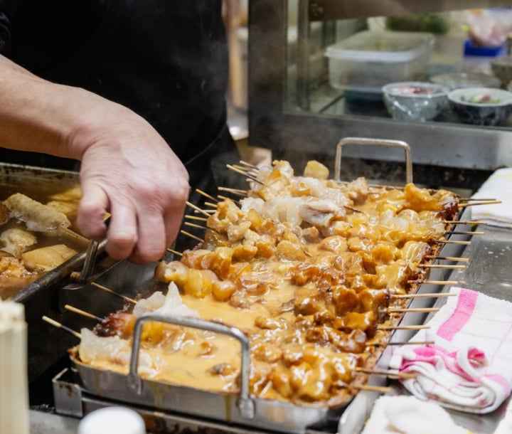串に刺した煮込みを鍋から取り分ける手元
