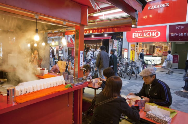 商店街の赤い屋台カウンターで食事をする人たち