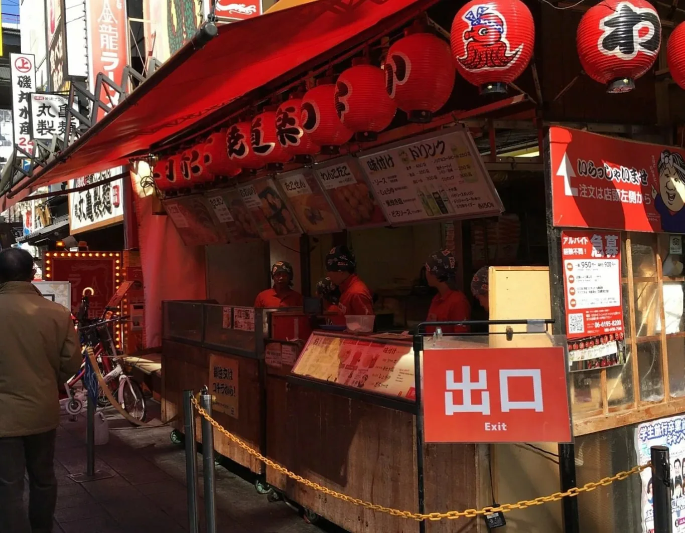 「出口」の札と赤い提灯が下がる屋台の店先