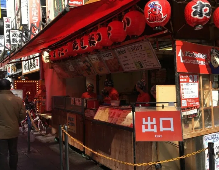 「出口」の札と赤い提灯が下がる屋台の店先