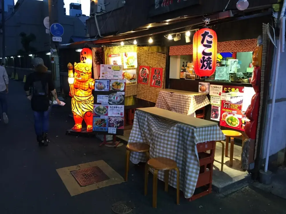 夜の路地に灯るたこ焼き屋の提灯とテーブル席