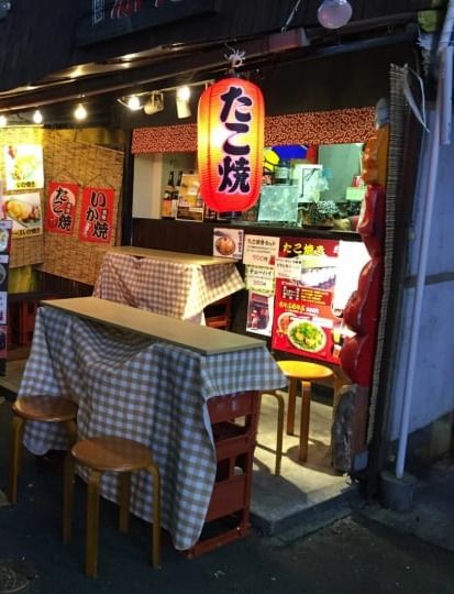 夜の路地に灯るたこ焼き屋の提灯とテーブル席